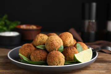 Delicious falafel balls with lime on wooden table, closeup