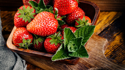 Fresh juicy strawberries with leaves on a wooden background