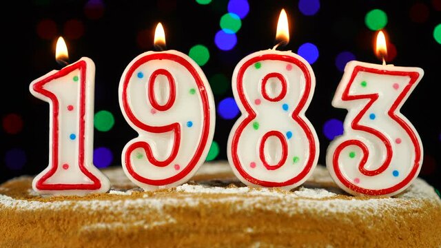 Birthday cake with white burning candles in the form of number 1983