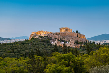 Fototapeta na wymiar Evening view of the Parthenon Temple at Acropolis hill, in Athen, Greece. The famous old Acropolis is a top landmark of Athens. Scenic view of remains of ancient Athens.