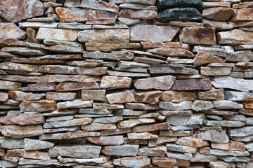 Texture of a stone. Old stone wall texture background. Grey stone wall as a background or texture. Stone wall of natural stones in different sizes. Side covering with natural stones.