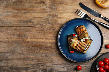 Delicious baked eggplant rolls served on wooden table, flat lay. Space for text