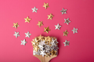 Top view of the wooden brush on the pink background,with silver and golden stars above.Greeting card with copy space.