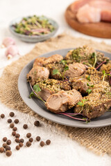 Stewed turkey fillet with sprouts of radish on white wooden background. Side view, selective focus.