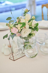 Beautiful floral arrangement of rose flowers and greenery on wedding table in restaurant, copy space. Luxury wedding decorations. Table setting