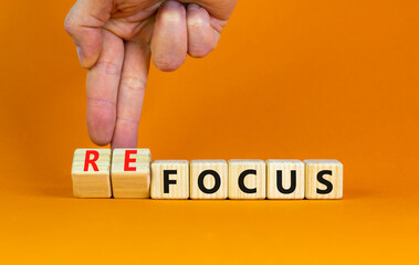 Focus or refocus symbol. Businessman turns wooden cubes and changes the word focus to refocus. Beautiful orange table orange background, copy space. Business, focus or refocus concept.