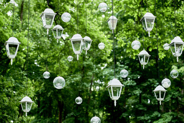 Luxury wedding decorations outdoors on green background, copy space. Lanterns and bulb garland on...