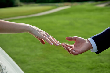 Newlywed couple's hands with wedding rings on golf course background, copy space. Wedding couple,...