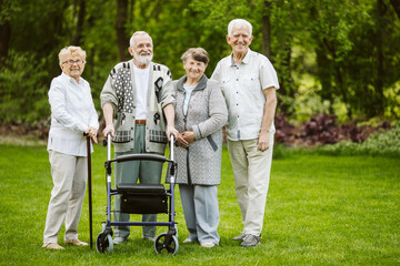 Senior man with walker during walk in the park of modern nursing home