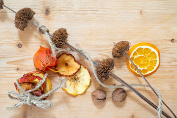Trockenblumen mit getrockneten Apfelringen, Orangen, Nüssen und dekorativer Schnur