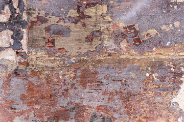 Wall background with different layers of cracked and worn paint.
