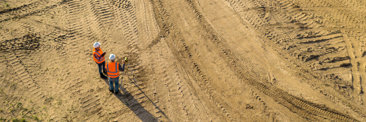 Top view of two road construction workers in orange vests and pr - 472077574