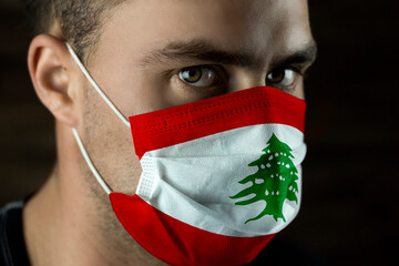 Young man in a medical mask with the flag of Lebanon on the mask