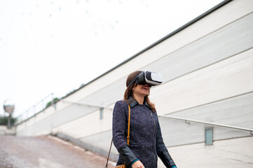 Fototapeta premium Happy Young woman walking in a city wearing virtual reality glasses.