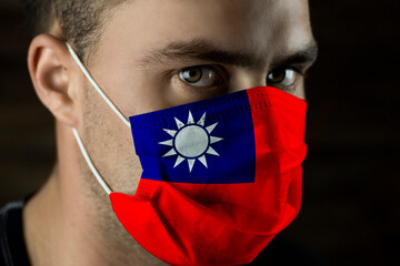 Young man in a medical mask with the flag of Taiwan on the mask