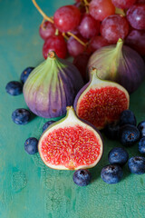 Top view of figs, pink grapes and blueberries on a green old table.