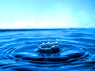Naklejka na ściany i meble A blue drop drips into the water and creates splashes of various shapes
