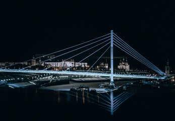 Night city. Urban architecture. Illuminated bridge over the river.