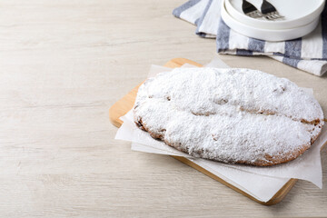 Delicious Stollen sprinkled with powdered sugar on wooden table, above view. Space for text