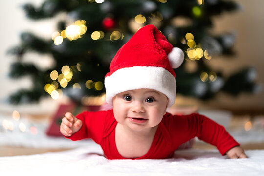 adorable little baby boy in a red christmas outfit on a soft fake fur in front of a christmas tree
