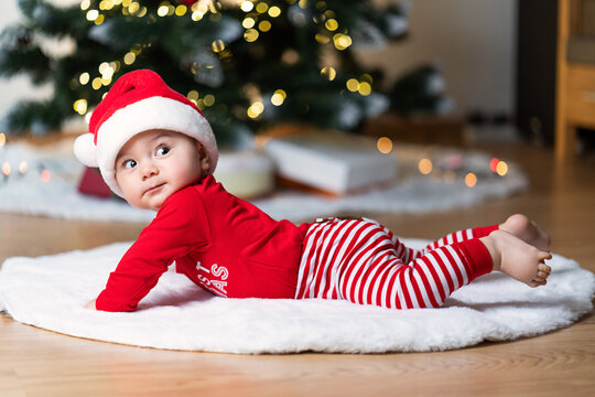 adorable little baby boy in a red christmas outfit on a soft fake fur in front of a christmas tree