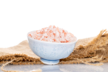 Crystals of Himalayan salt in a ceramic pot, close-up, isolated on white.