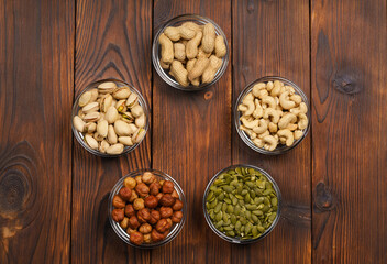 Pistachios, hazelnuts, peanuts, pumpkin seeds, cashews on a wooden table. Portions of nuts on a wooden table. Assorted nuts.