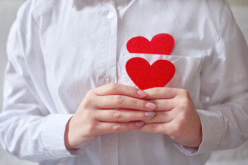 woman hands holding a heart and shape of heart in pocket of white shirt. shallow depth of field horizontal photo