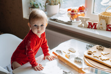 Cute little baby toddler girl making christmas cookies in home kitchen and play with dough. Mother...