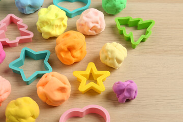 Different color play dough with molds on wooden table