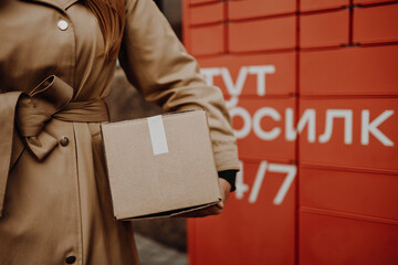 Woman picks up mail from automated self-service post terminal machine on the street. Parcel...