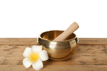 Golden singing bowl, mallet and flower on wooden table against white background