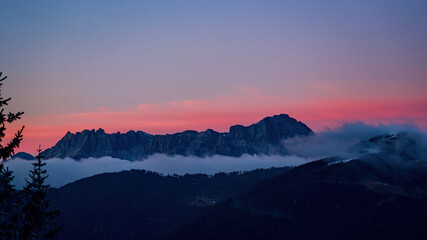 Fototapeta premium breathtaking sunset at a cold autumn evening on the mountains with view of the alps witha pink sky and fog in the valley
