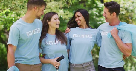Portrait of smiling diverse group of friends in volunteer blue t shirts rubbish collecting in park