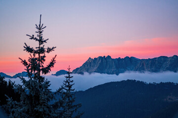 breathtaking sunset at a cold autumn evening on the mountains with view of the alps witha pink sky and fog in the valley