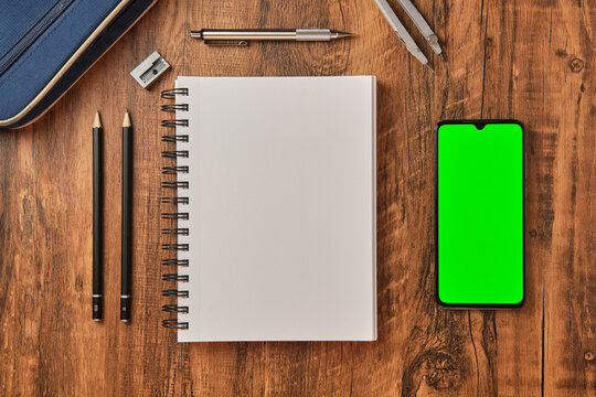 Concepto de dibujo y deseño con pantalla verde, lapices de trazado y cuaderno para bocetos sobre fondo de madera desde una vista cenital. 