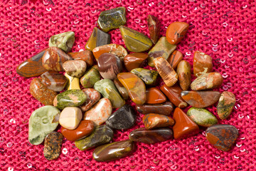 Red and multicolored jasper polished tumblestones on pink background