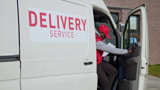 Couriers delivering parcel box to recipient. African american delivery man open a van side door and checked cardboard box package on a tablet folder.