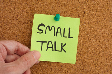 A man holding a sticky note that is pinned to a corkboard with the phrase Small Talk on it
