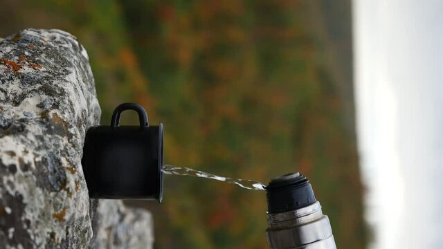 pours tea in nature in the mountains in autumn vertical