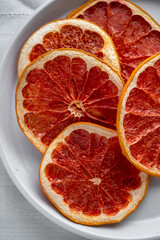 Dry grapefruit slices in a plate, top view. Homemade organic round citrus slices.