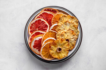 Homemade organic dried fruit slices. Dried orange, grapefruit, pineapples in a platel. Healthy snack or dessert.