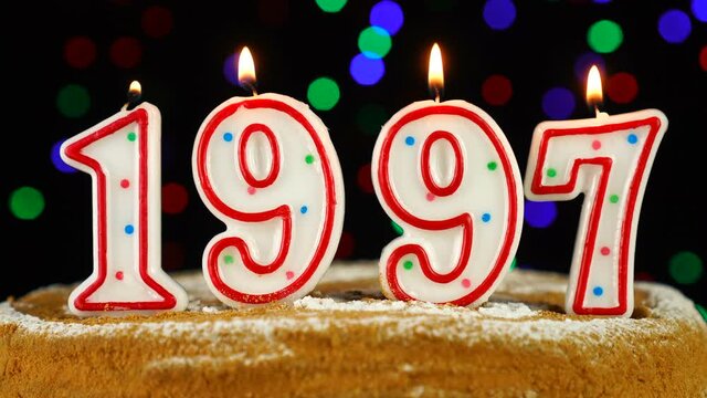 Birthday cake with white burning candles in the form of number 1997