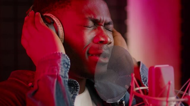 Emotional Black Guy Wearing Headphones Singing To Professional Microphone In Music Studio