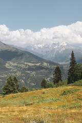 Mountain landscape near Mestia, Svaneti region, Georgia, Asia. Snowcapped mountains, Caucasus mountain range in the background. Blue sky with clouds above. Georgian travel destination