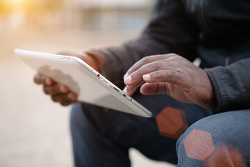 Obraz premium African american man uses tablet computer. Black mans hands holds a tablet pc