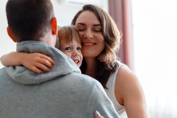 Happy family hugging. Little smiling child kid girl daughter hugs mom and dad lifestyle in home interiior. Family spending time together, enjoying time at home