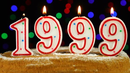 Birthday cake with white burning candles in the form of number 1999