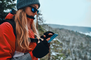 Portrait of a beautiful girl wearing sunglasses and gloves with open fingers holding a phone in her hands and using it. Copy space. - Powered by Adobe