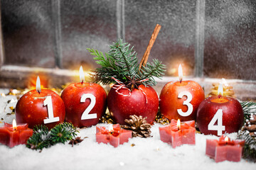 Beautiful card with advent candles and christmas apples in front of old window in snow. 4th advent, all 4 candles burning. Christmas Eve.